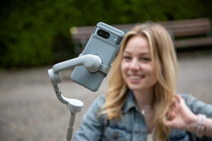 Frau mit Handy an Selfiestick fotografiert oder filmt sich selbst