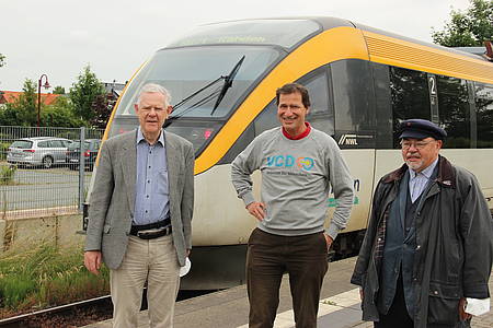 Drei Personen stechen vor Zug der gelben Eurobahn