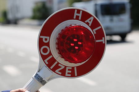 Rot-Weiße Polizeikelle mit der Aufschrit Halt