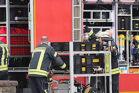 Zwei Feuerwehrmänner arbeiten am Einsatzwagen