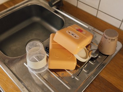 Geschirr und Kinderbrotdose steht zum Trocknen an einer Spüle.