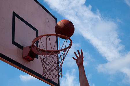 Hand wirft Ball in Basketballkorb
