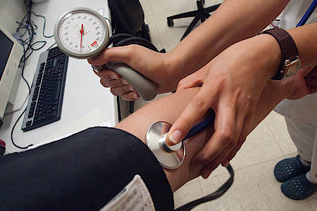 Frauenhände messen Blutdruck, Oberarm mit Manschette