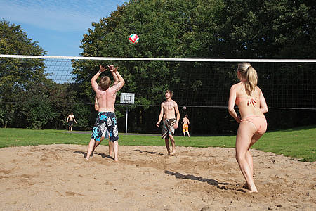 Männer und Frauen spielen Beachvolleyball im Sand