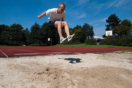 Mann springt in Sandgrube beim Weitsprung