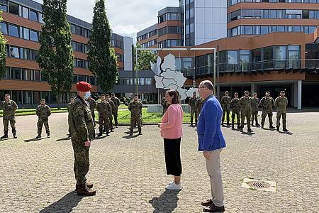 Soldaten stehen vor dem Kreishausgebäude eine Frau und eine Mann stehen mit dabei
